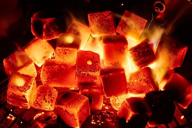 Glowing shisha charcoal cubes in a fire